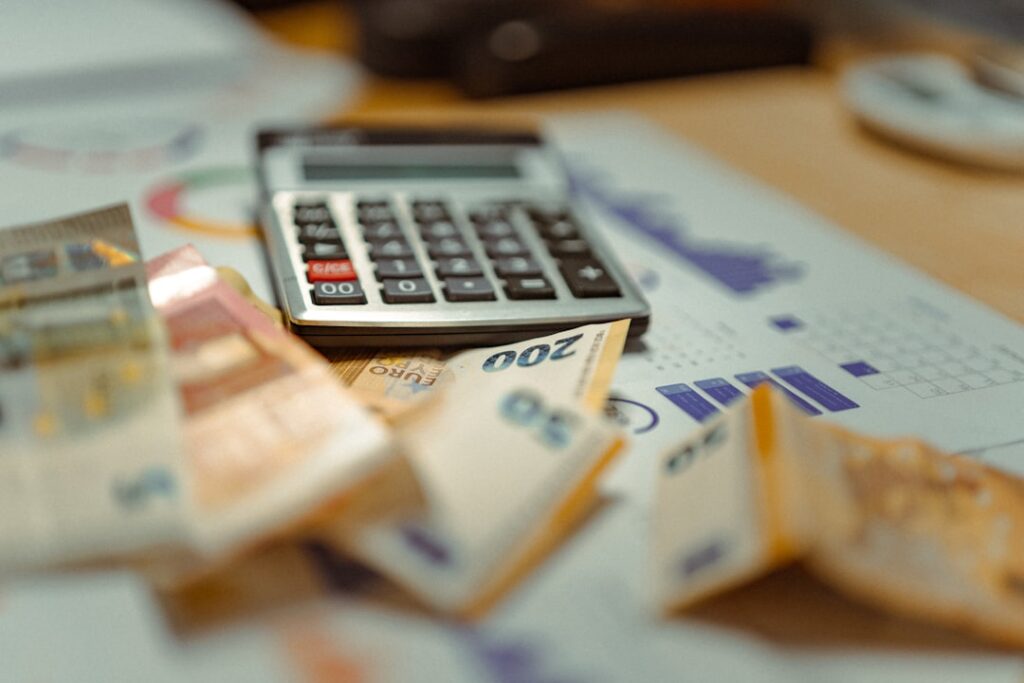 Calculadora, notas e documentos financeiros representando análise de custos imobiliários