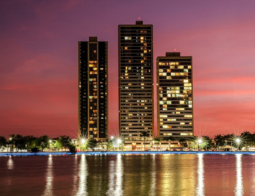 Edifícios residenciais de alto padrão iluminados ao entardecer representando o mercado imobiliário de luxo
