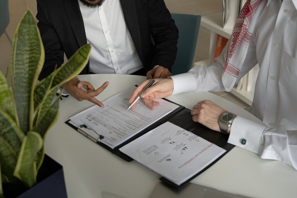 Two professionals in business attire reviewing legal documents and contracts on a table