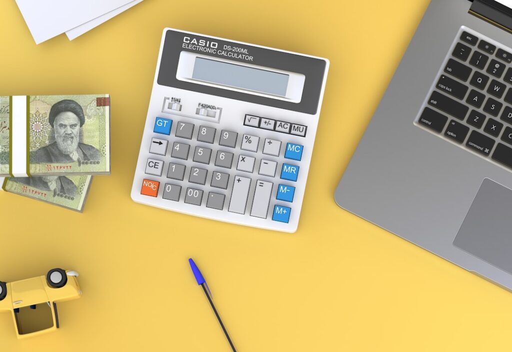 Calculadora e laptop representando o planejamento de custos para regularização de imóveis