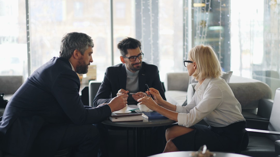 Professional consultation meeting with three people sitting around a table discussing documents