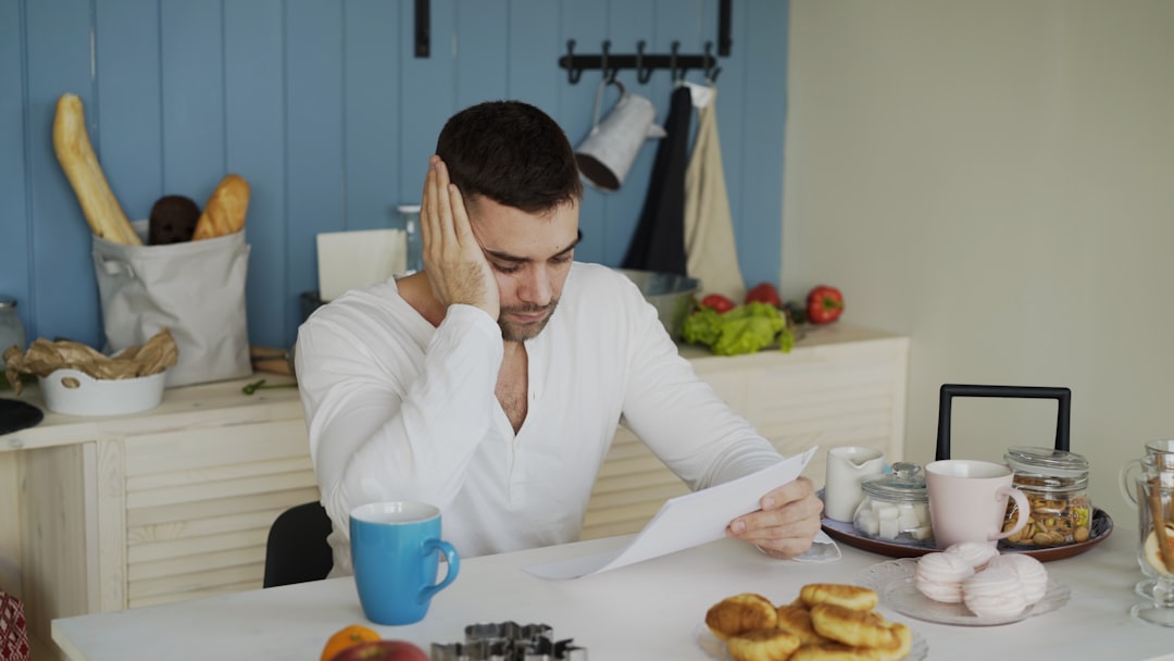 Upset young man reading unpaid bill in kitchen - Photo by Jeremy Wong Weddings