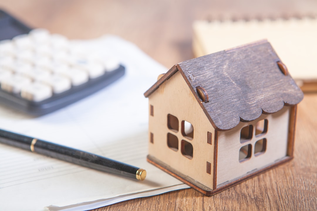Wooden house model with pen and notebook representing real estate legal documentation and property law consultation