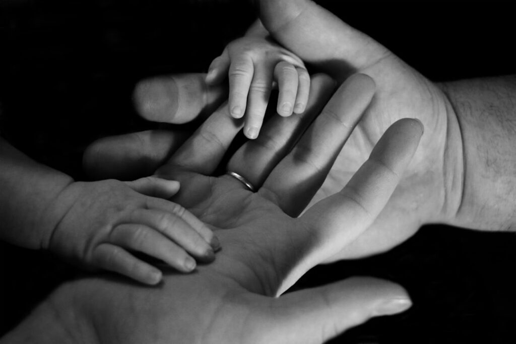 Baby's hand held by adult hands representing family protection and care in family law matters