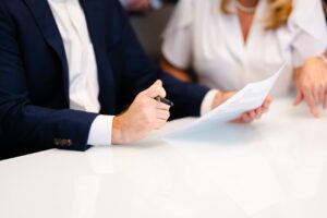 Profissional em terno revisando documento jurídico com outra pessoa em reunião — advogado de direito imobiliário