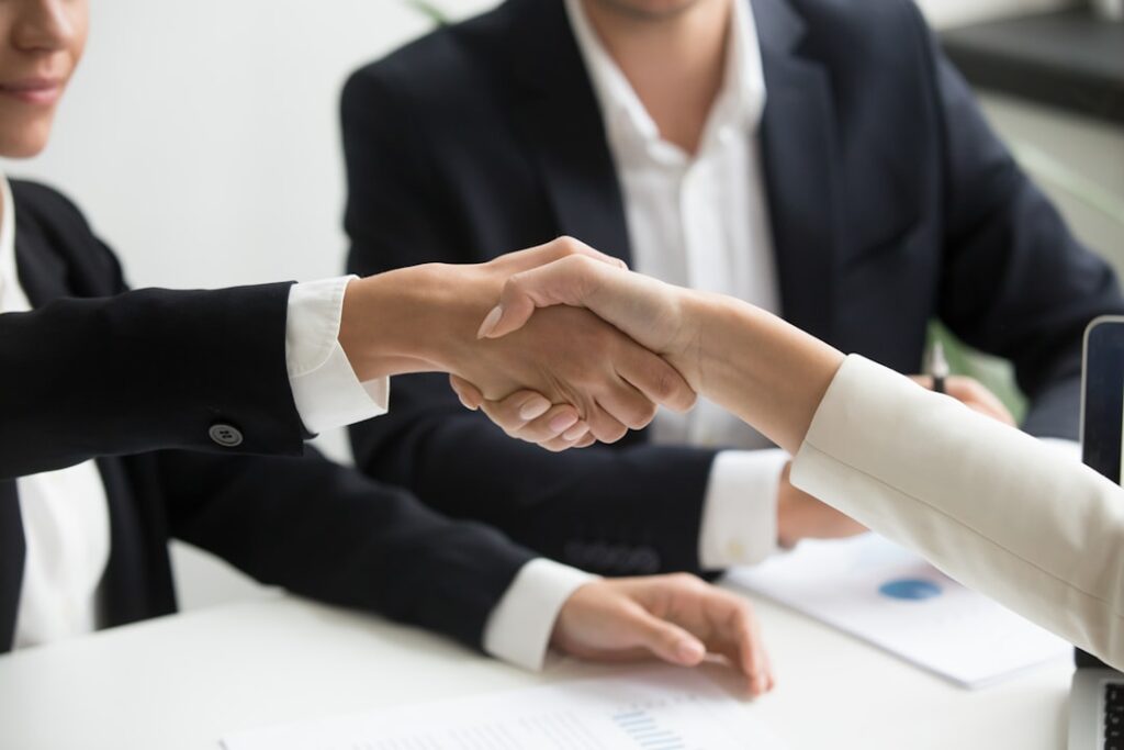 Pessoas apertando as mãos em reunião de negócio representando negociação de distrato imobiliário