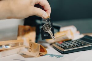 Mão segurando chaves de casa com calculadora e documentos financeiros sobre mesa, representando decisões no distrato imobiliário