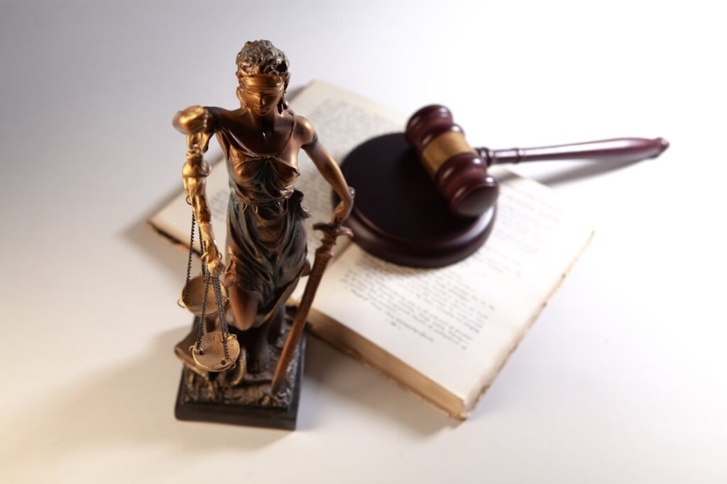 Estátua da Justiça, martelo judicial e livros de direito representando especialização e conhecimento legal