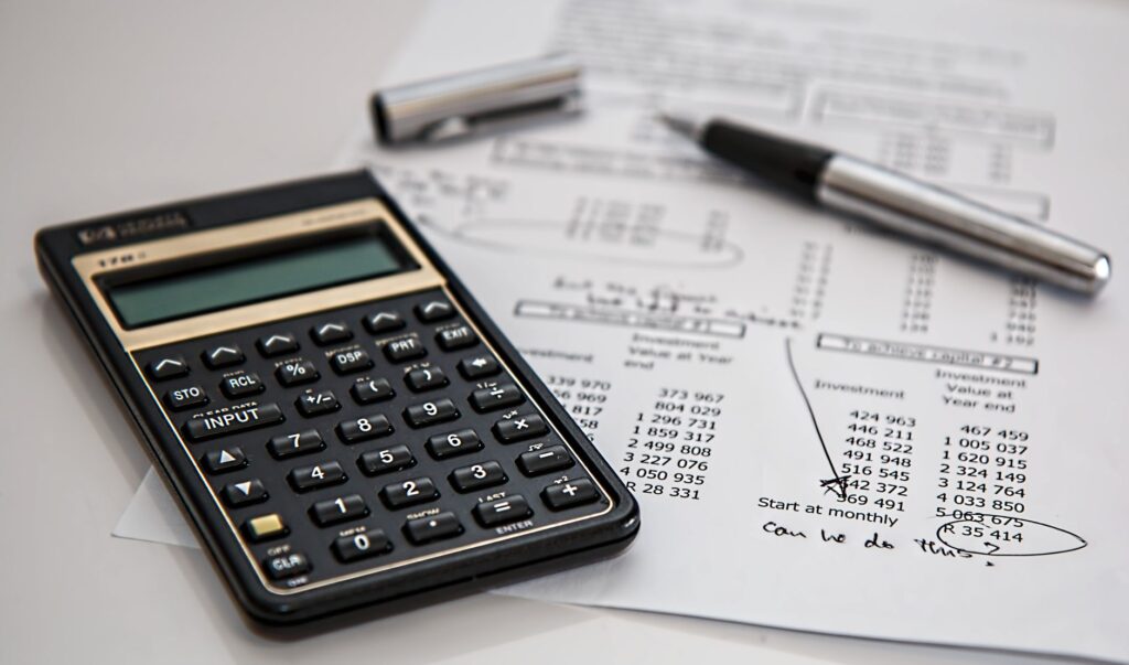 Calculadora sobre documentos financeiros e caneta, representando o cálculo da base de renda para fixação da pensão alimentícia