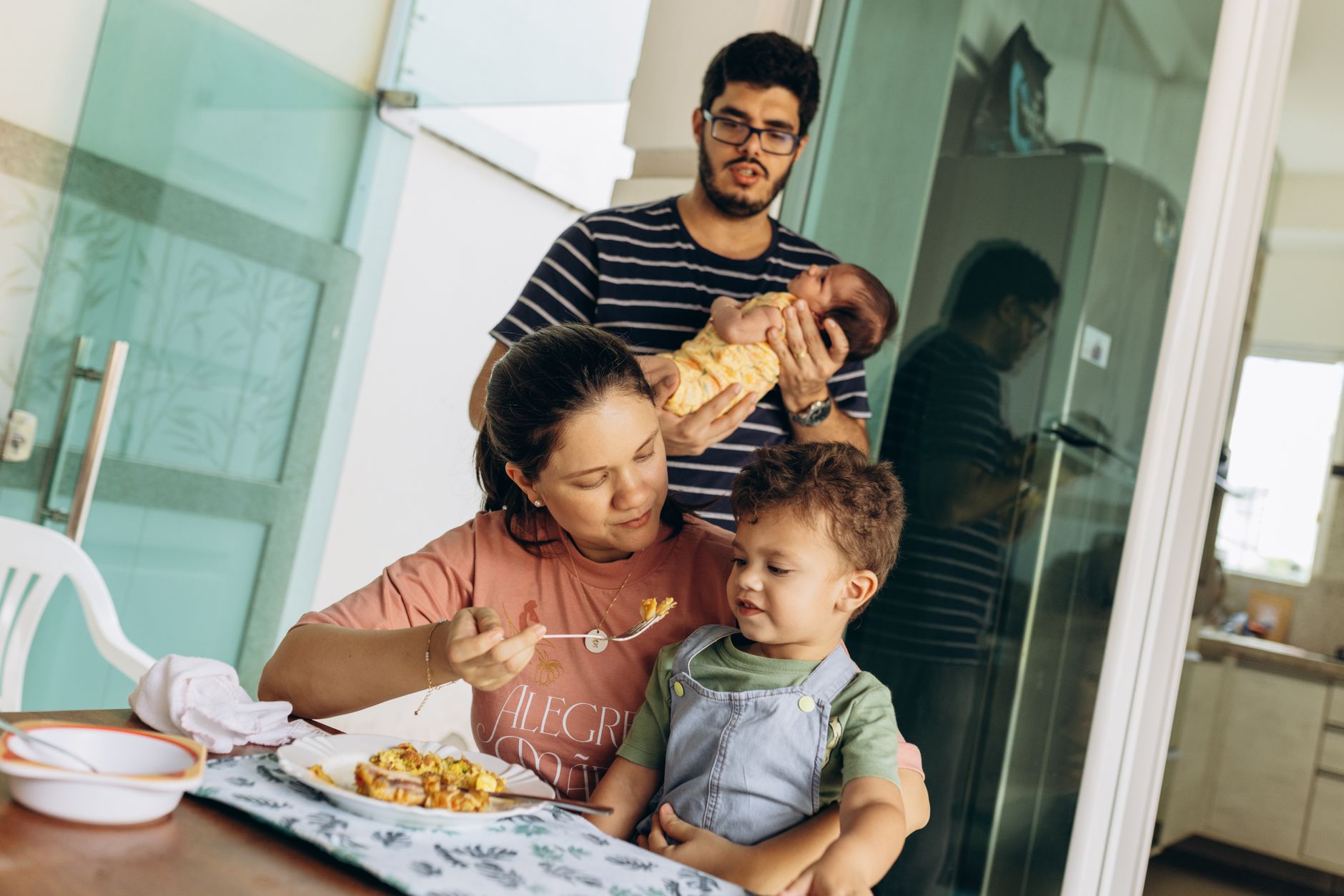 Família brasileira com dois filhos sentada à mesa durante refeição, representando o contexto de pensão alimentícia para 2 filhos
