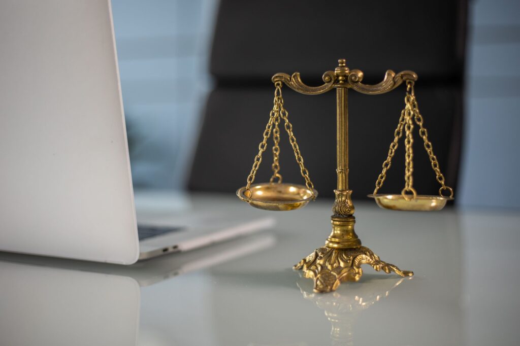 Balança da justiça ao lado de notebook representando atendimento jurídico previdenciário online