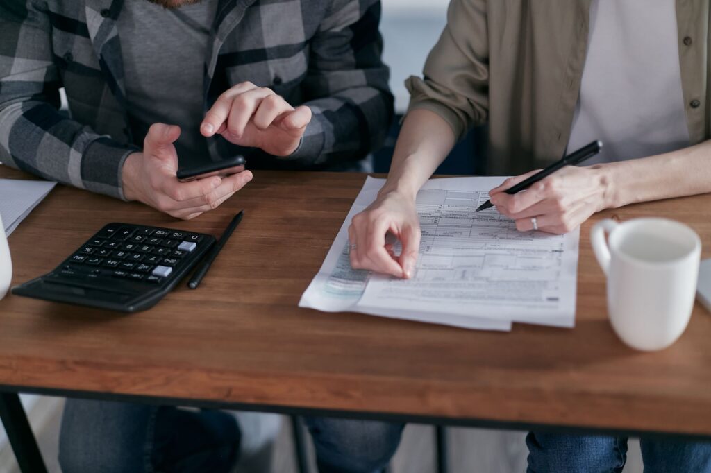 Duas pessoas analisando formulários de imposto com calculadora sobre mesa de madeira, representando o planejamento tributário do ITCMD no Rio de Janeiro.