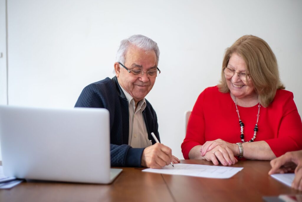 Casal de idosos assinando documentos em reunião de planejamento previdenciário