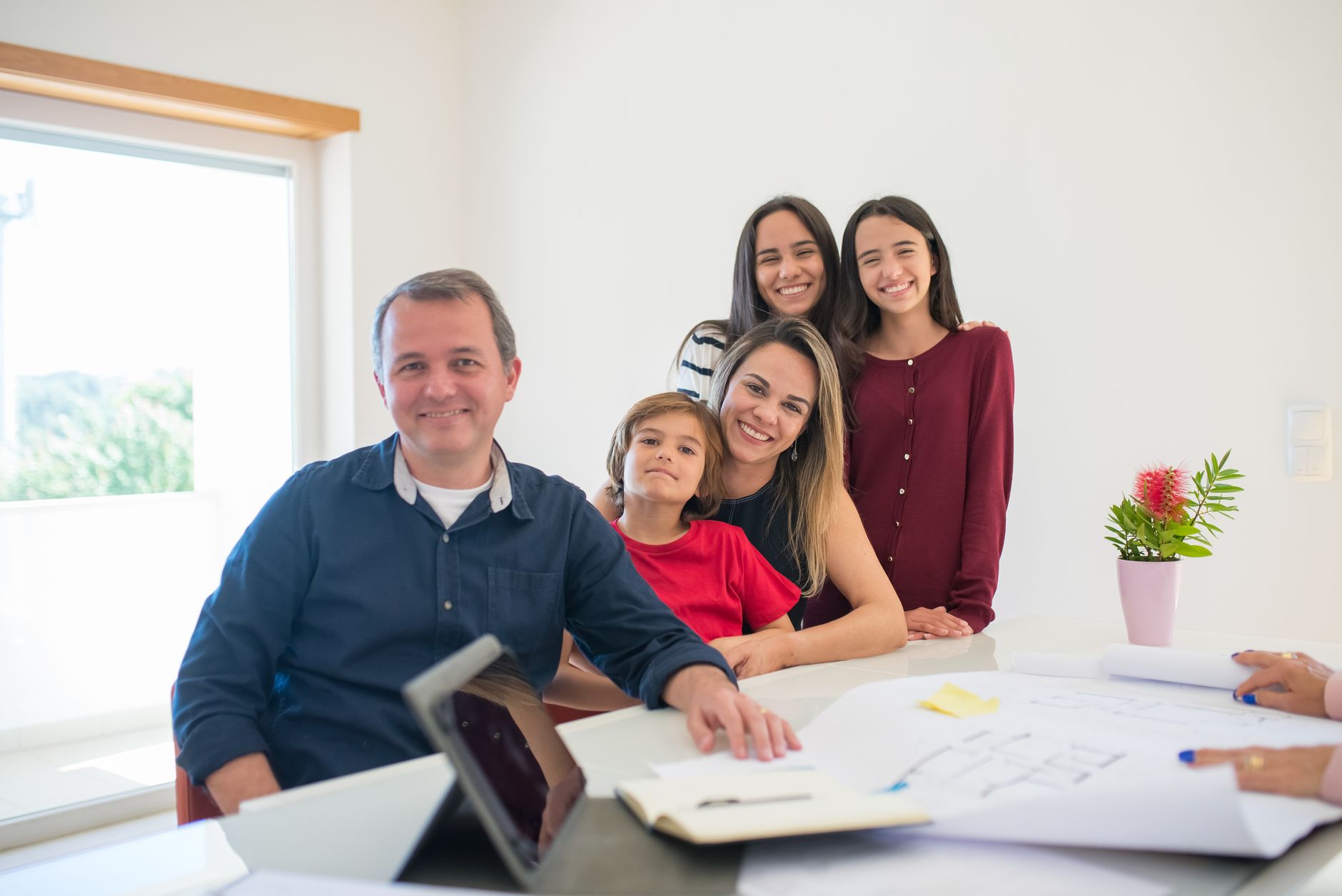 Família brasileira reunida em planejamento sucessório com documentos e planta na mesa