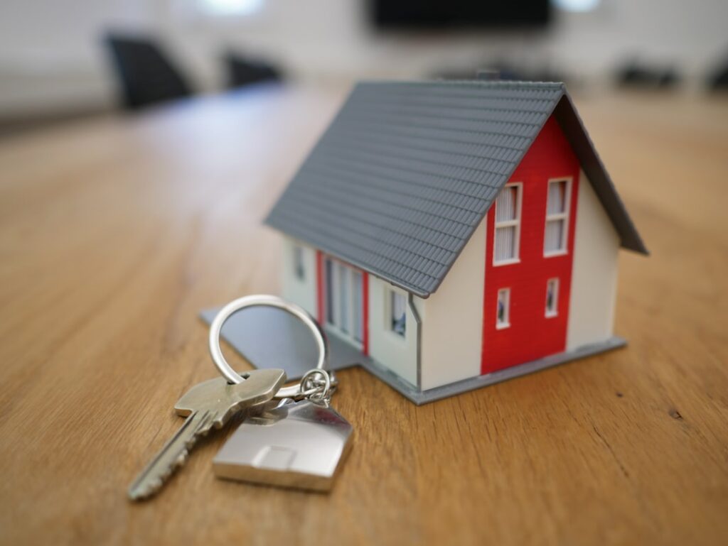 Miniatura de casa ao lado de chaves de imóvel sobre mesa, representando herança de imóvel no inventário