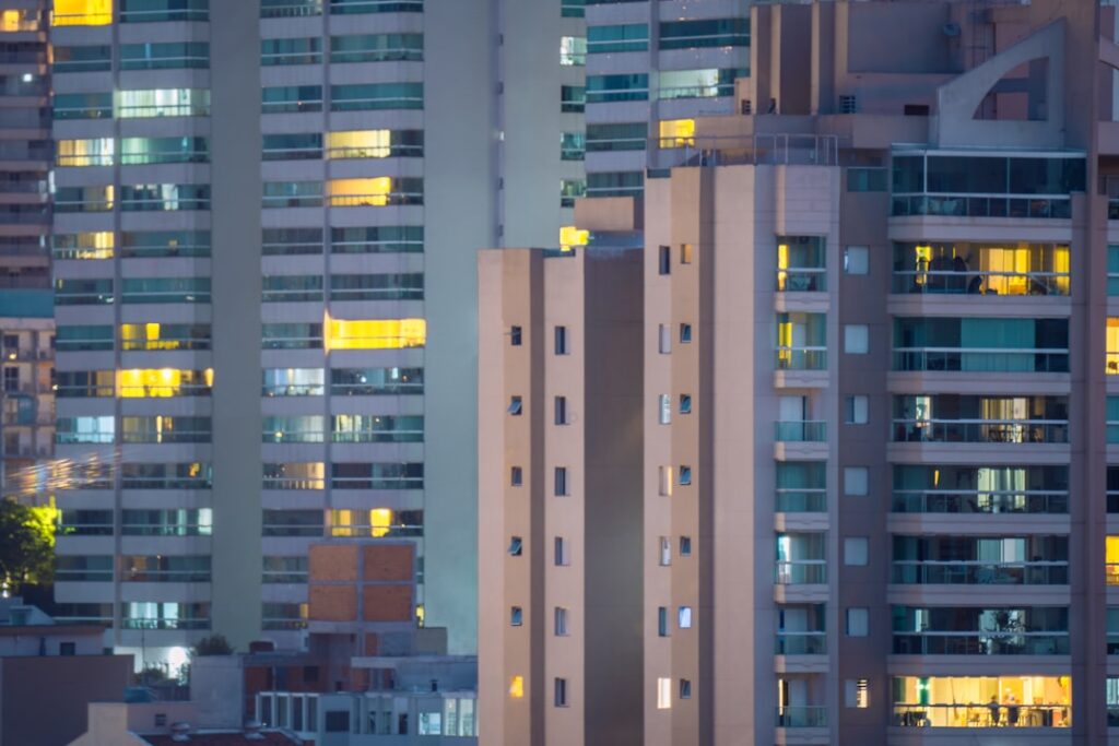 Prédios de apartamentos iluminados à noite em área urbana brasileira, ilustrando imóveis sem regularização de propriedade