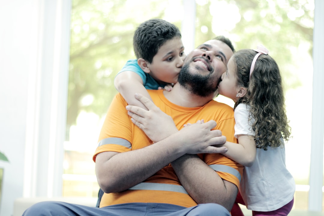 Pai sendo abraçado e beijado por dois filhos, representando a pensão alimentícia para 2 filhos