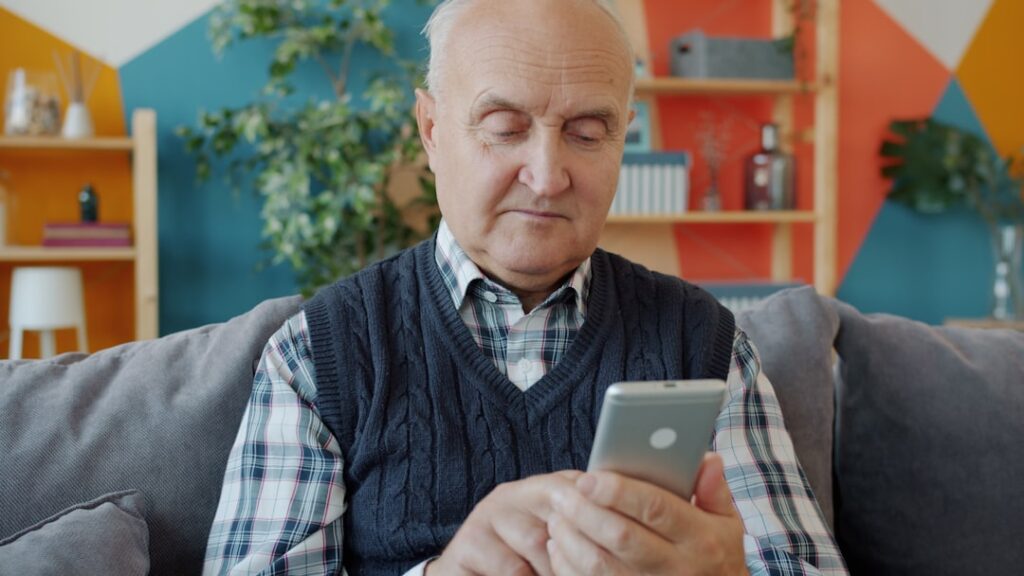 Homem idoso usando smartphone para acessar o aplicativo Meu INSS e simular sua aposentadoria