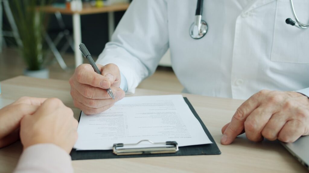Médico preenchendo laudo em consulta com paciente, representando a perícia médica do INSS para benefícios por incapacidade