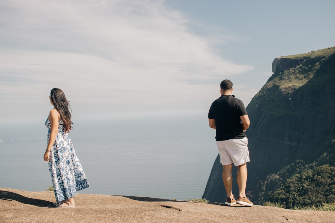 Casal separado em penhasco no Rio de Janeiro, representando divórcio e partilha de bens na Barra Olímpica RJ