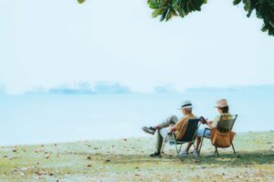 Casal de idosos aposentados relaxando tranquilamente à beira-mar, representando a liberdade da aposentadoria pelo INSS